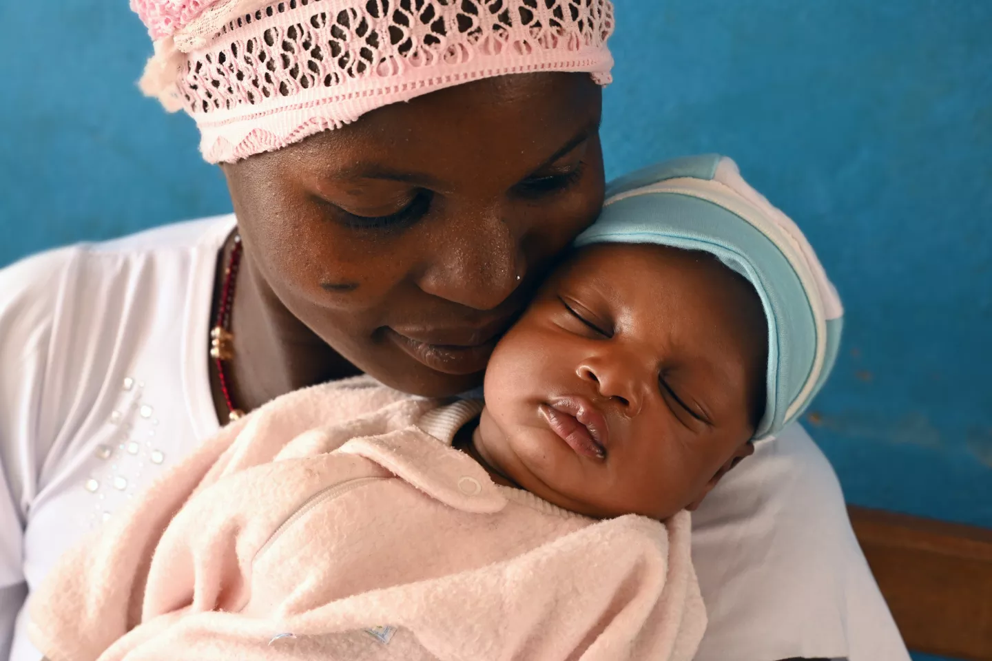 A young mother holding her sleeping baby.