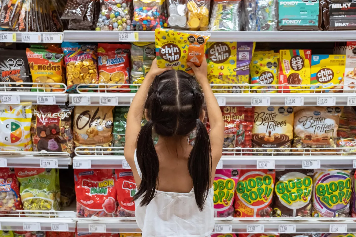Per&uacute;. Una ni&ntilde;a se estira para tomar un paquete de dulces de un estante en un supermercado de Lima.