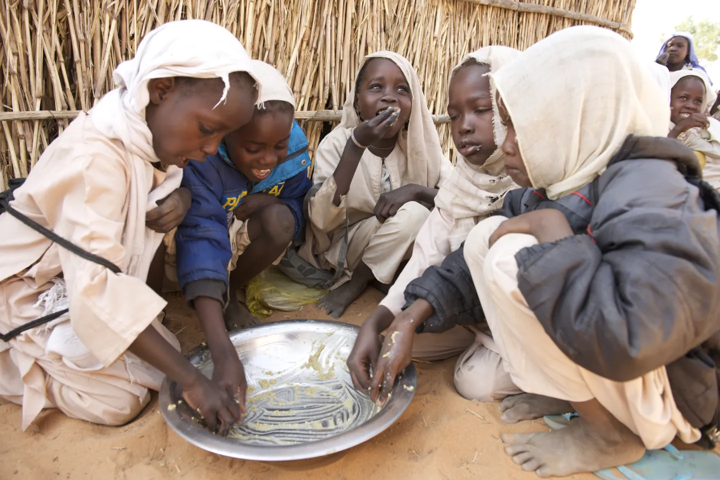 Sitting on a dirt floor outside their classroom, a group of young girl share a meal during lunch time at Salam #9 Primary School for Girls in Abu Shouk camp for Internally Displaced People.