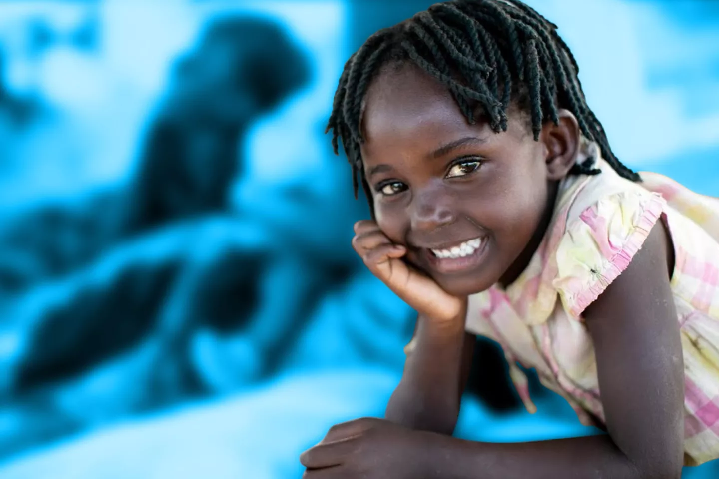 A young girl resting her head on her hand smiling