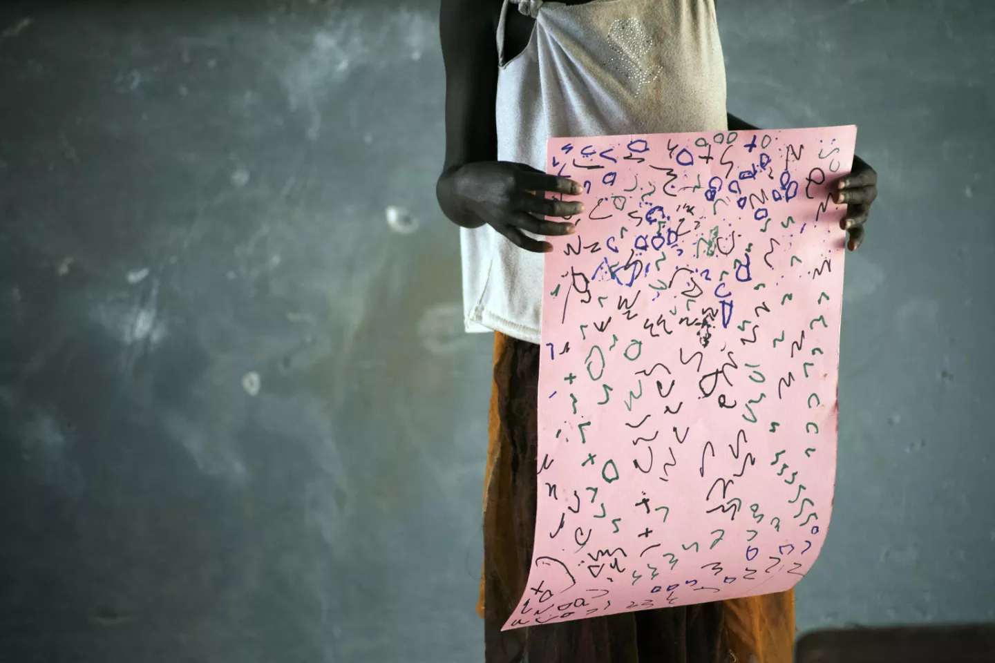 A girl holds up a poster of her drawings.