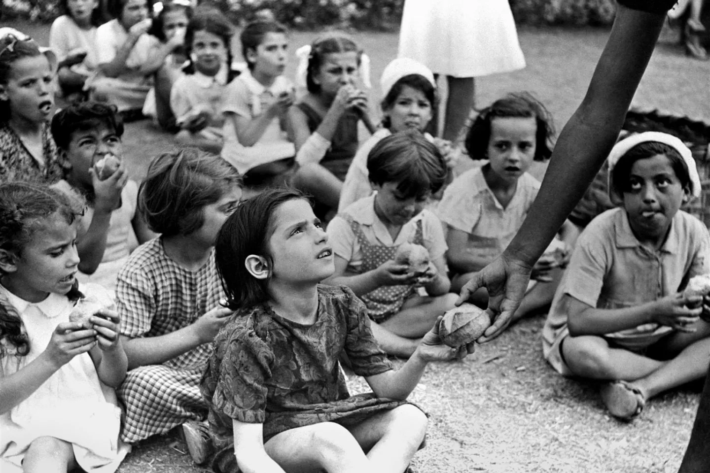 Children seated on the ground accepting food