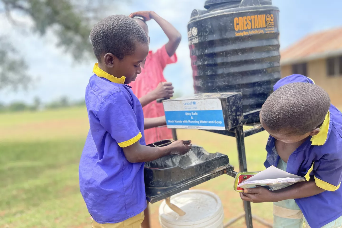 Edwin Byakatonda (left), a Primary 2 pupil at Buduma Primary School, Namayingo, using one of the five handwashing facilities that were supplied by UNICEF with funding from SIDA.