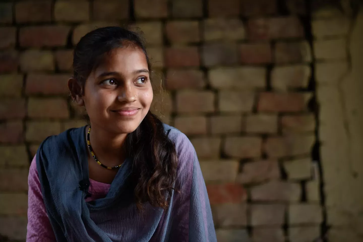A teen girl in Nepal smiles off into the distance.