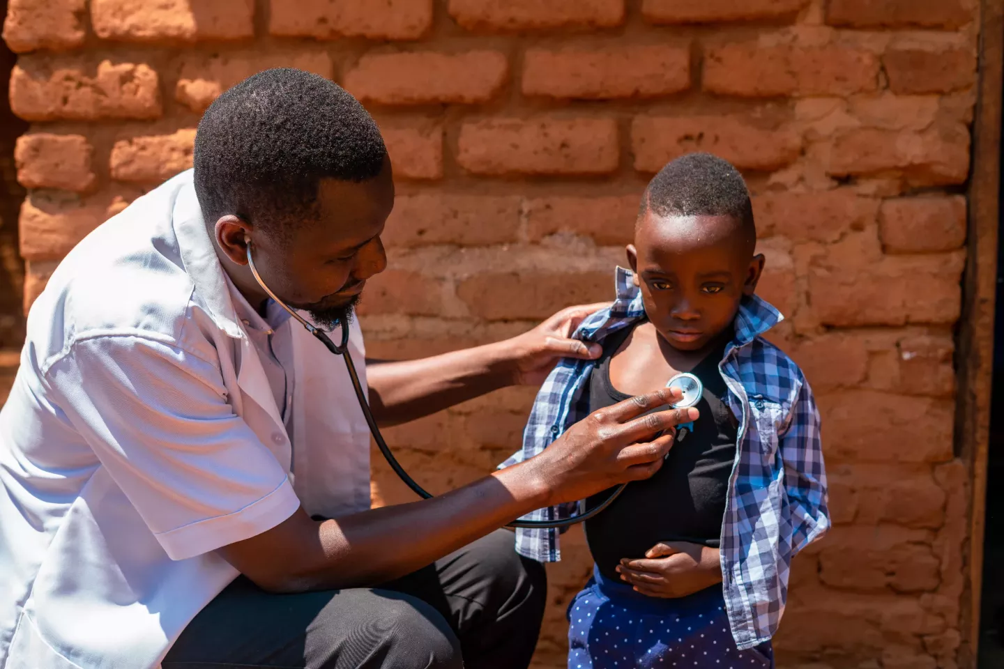 A health care worker conducts a check ups on a young boy in Malawi.