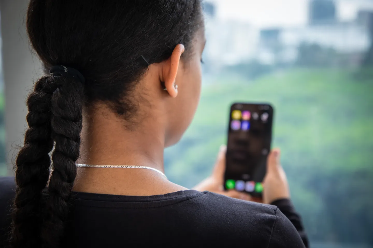 A view over the shoulder of a girl looking at her mobile phone.