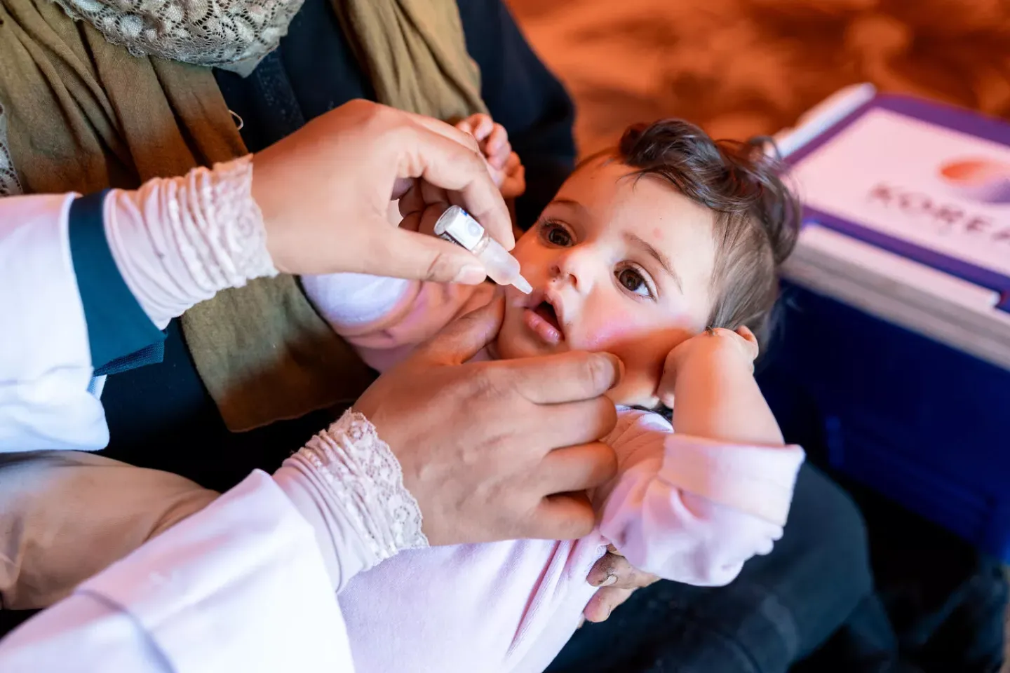 Siham, 9 months, is held by her grandmother Mariam as she receives an OPV vaccine from a health worker in Ajloun, Jordon.