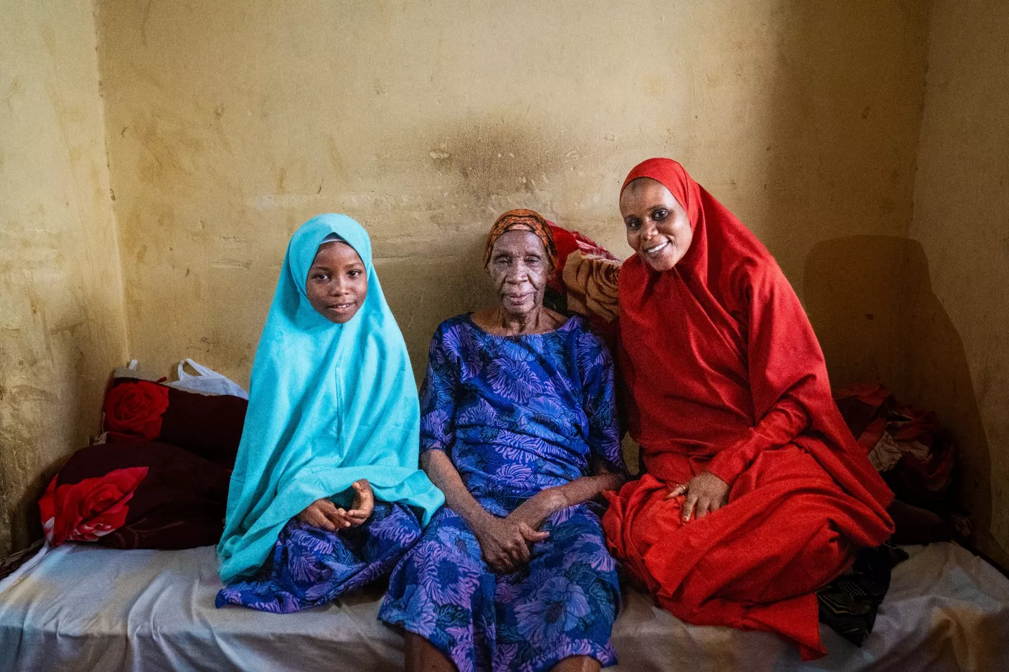 Fatima Habibu, 99, sits with her grand and great-grand daughters, Volunteer Community Mobilizer (VCM), Shamsiyya Abdullahi Jariri, 30, left and Mariyatu, Gidado, 9, at her home in Katsina, Nigeria on 30 May, 2024.