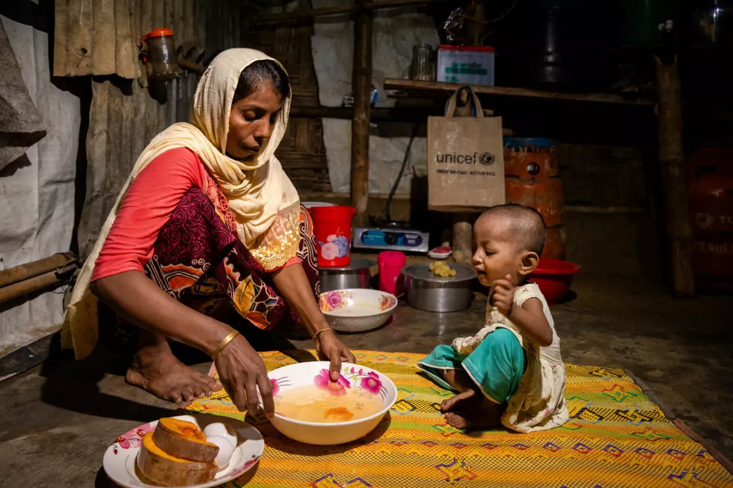 Bangladesh. A woman prepares a meal for her young daughter.