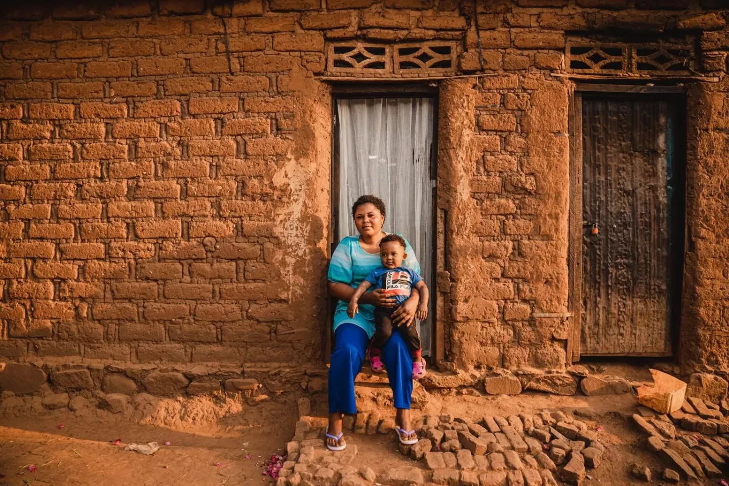 A 1-year-old child who survived mpox sits on his mother lap outside their home in Kamanyola, DRC. 
