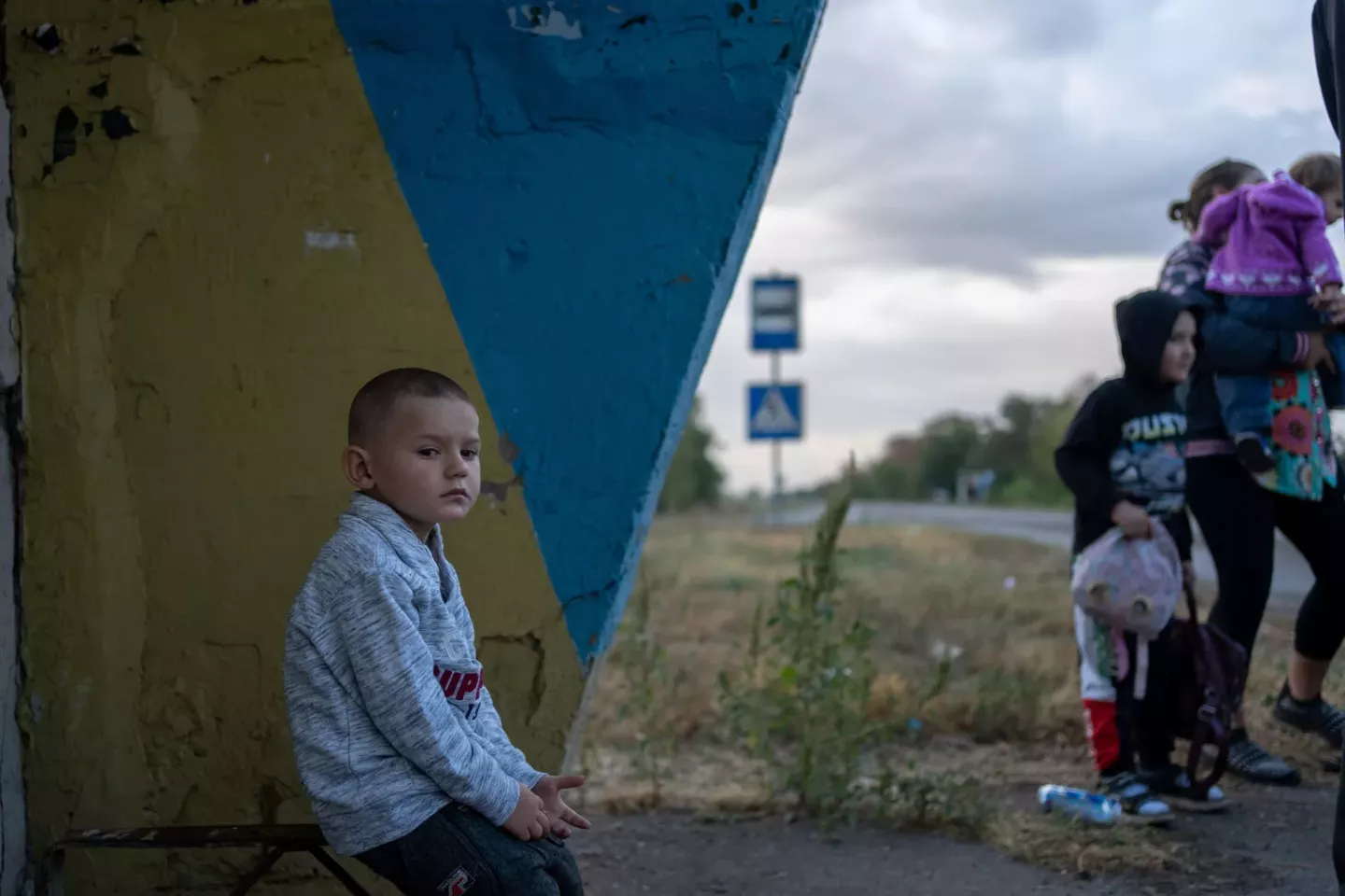 Ukraine. A boy sits at a bus shelter.