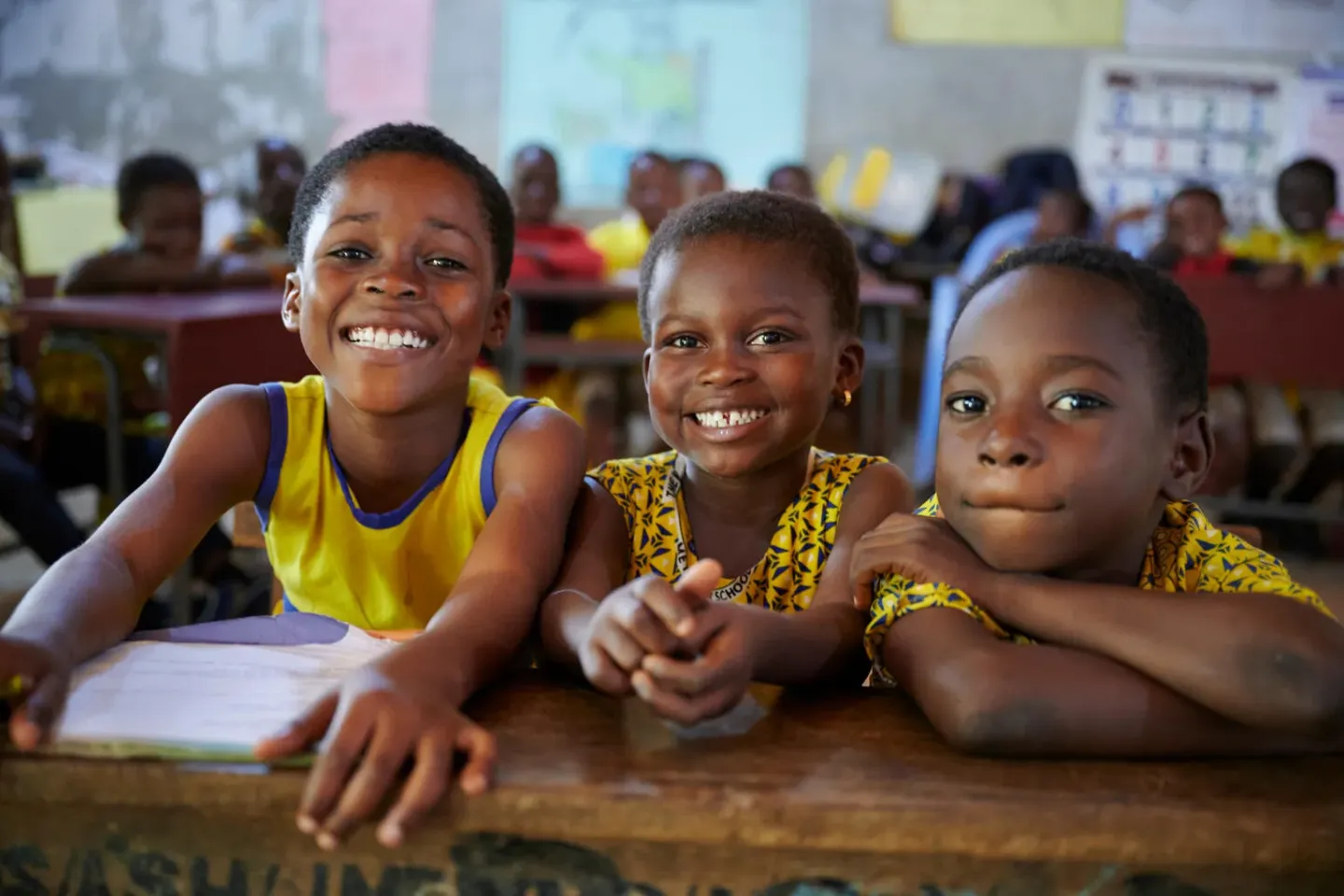 Ghana. Children smile as they sit at a desk in a math class in Juaben Municipality in Ashanti Region .