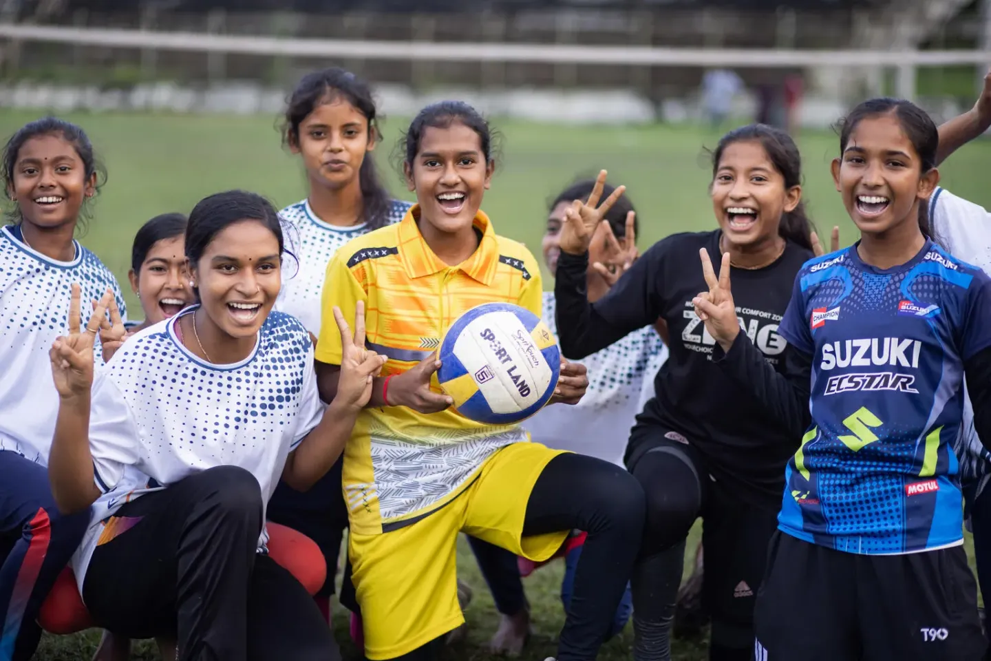 Young girls' volleyball players stand happily for a picture.