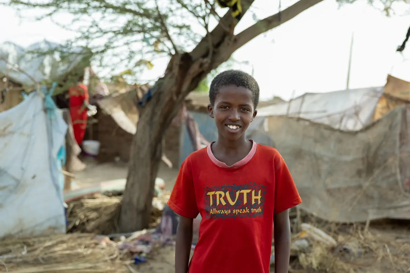A boy stands near his home in a gathering site for internally displaced families in Atbara, River Nile State