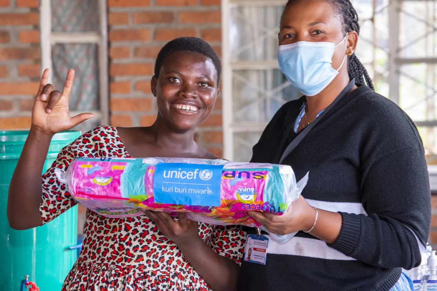 Menstrual health in Rwanda: A supply distributor handing out new packages of menstrual pads to a girl 