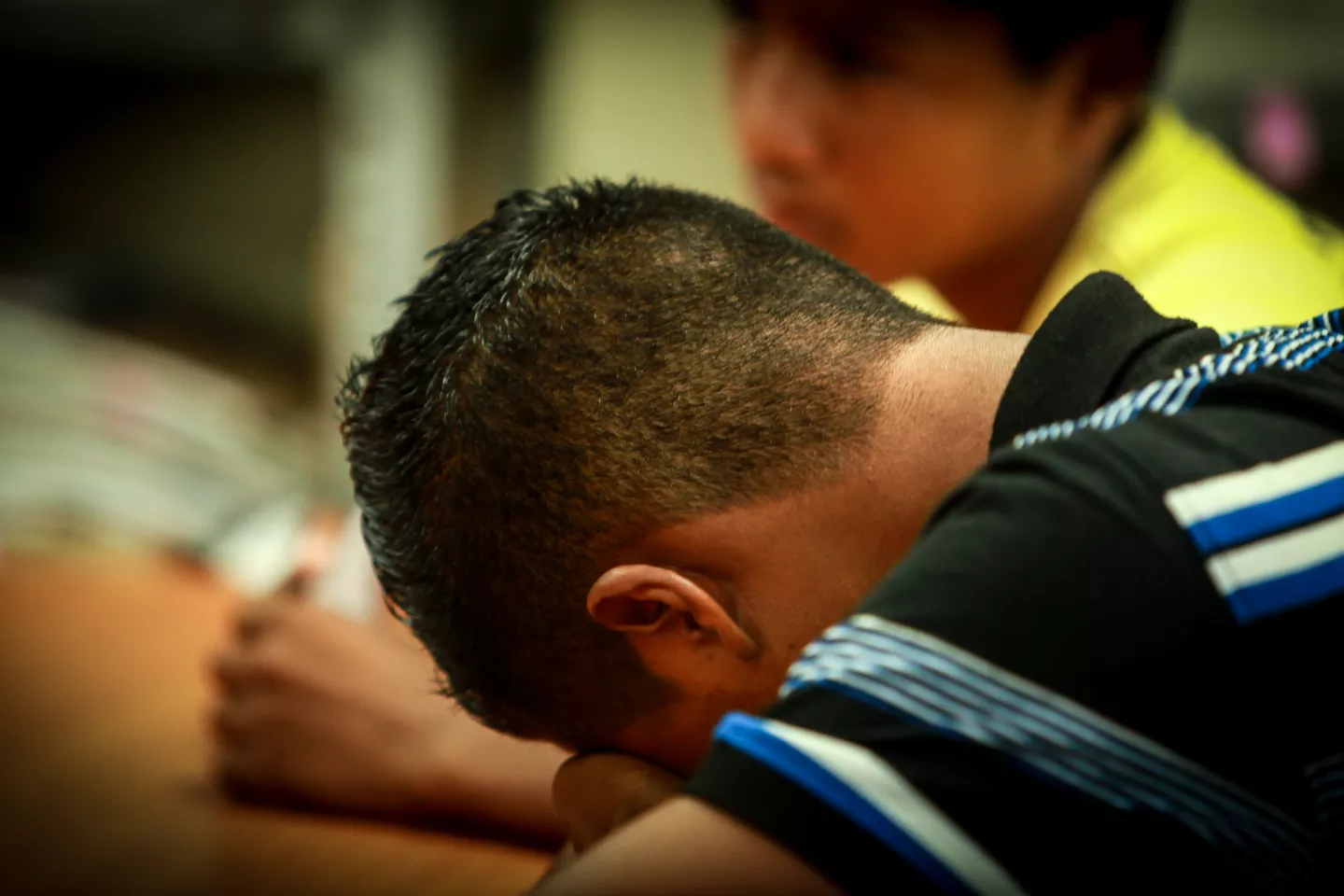 A boy puts his head down on a desk, El Salvador