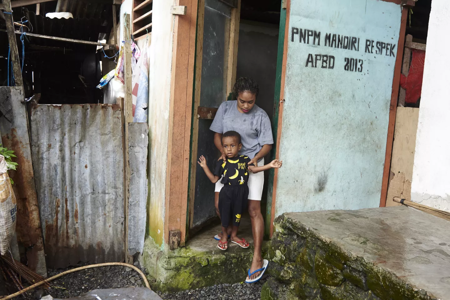 Sanitation inIndonesia: woman helps her child in using the family latrine. 