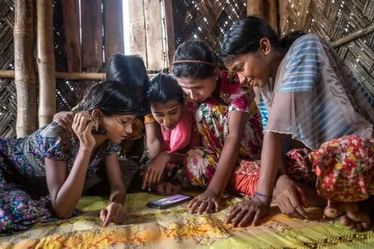 Refugee girls in Bangladesh playing on a cell phone.