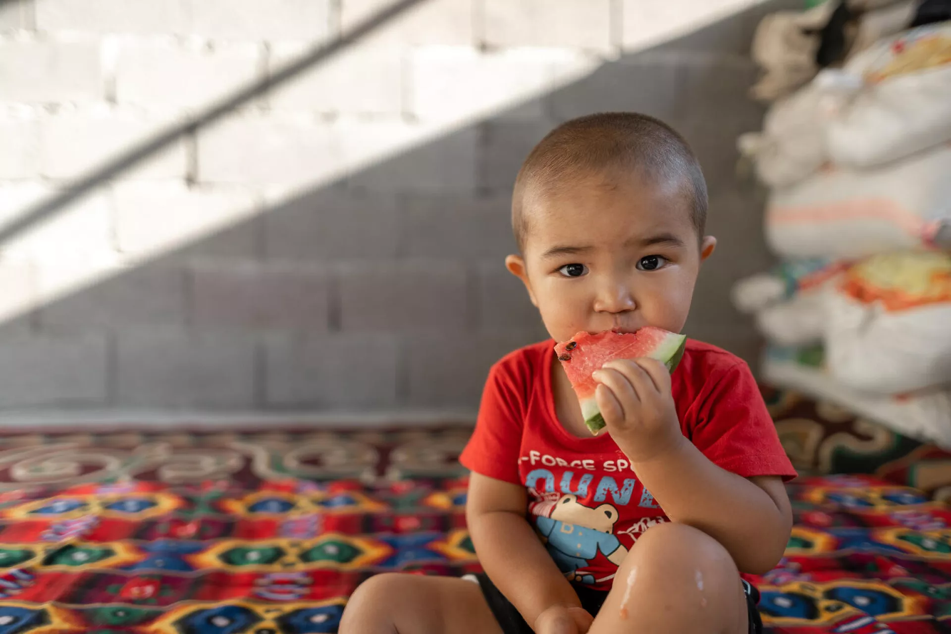           a two years old child, eating watermelon