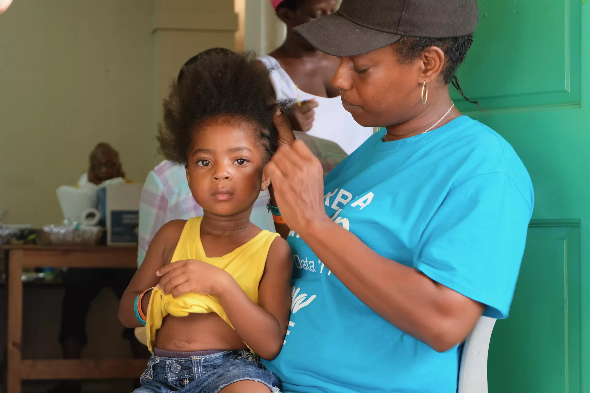A woman braids her daughter's hair, Antigua