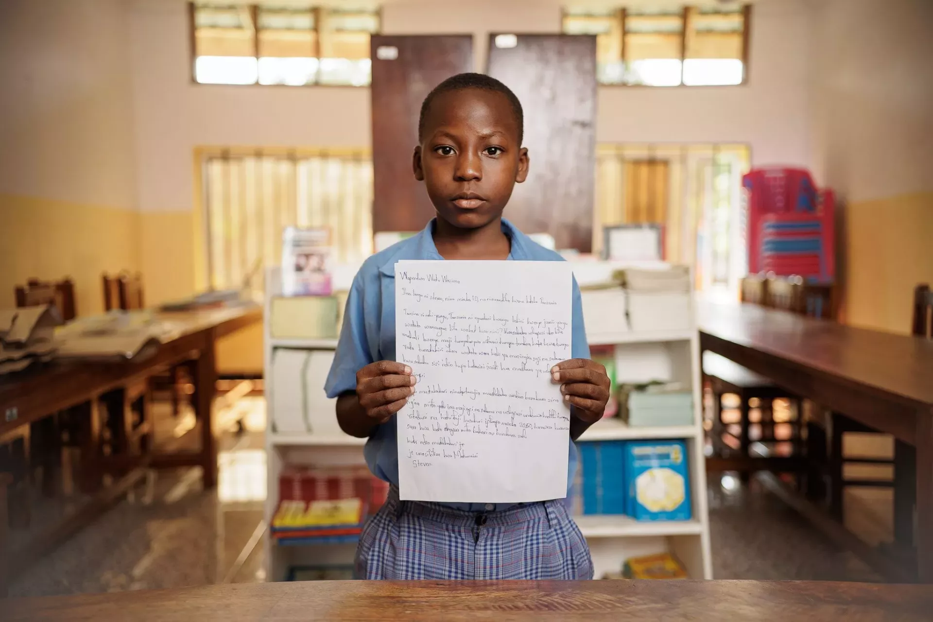 A boy in Tanzania holds up his letter written to the world's adults.