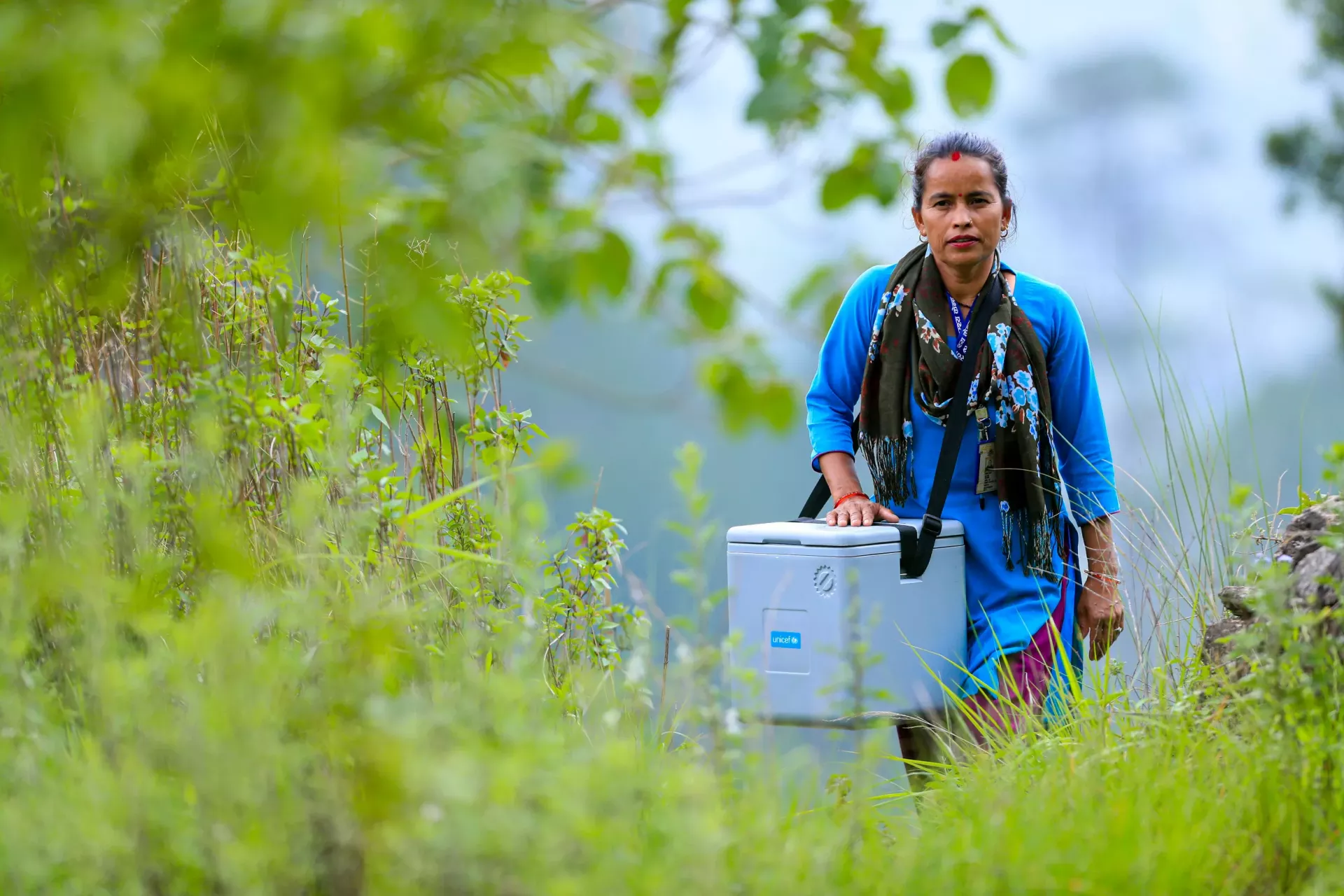 A woman health worker carrying a cooler box vaccine carrier