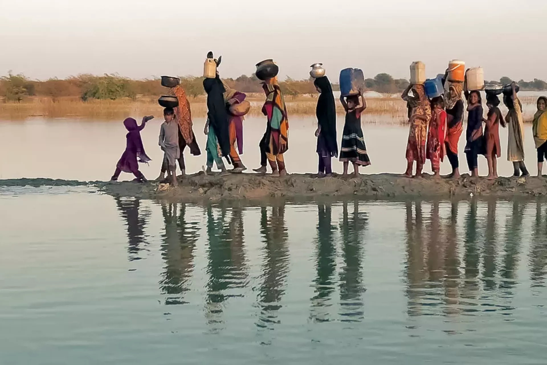 Women and girls walking with their buckets to fetch water in an inundated region of outhern Pakistan.