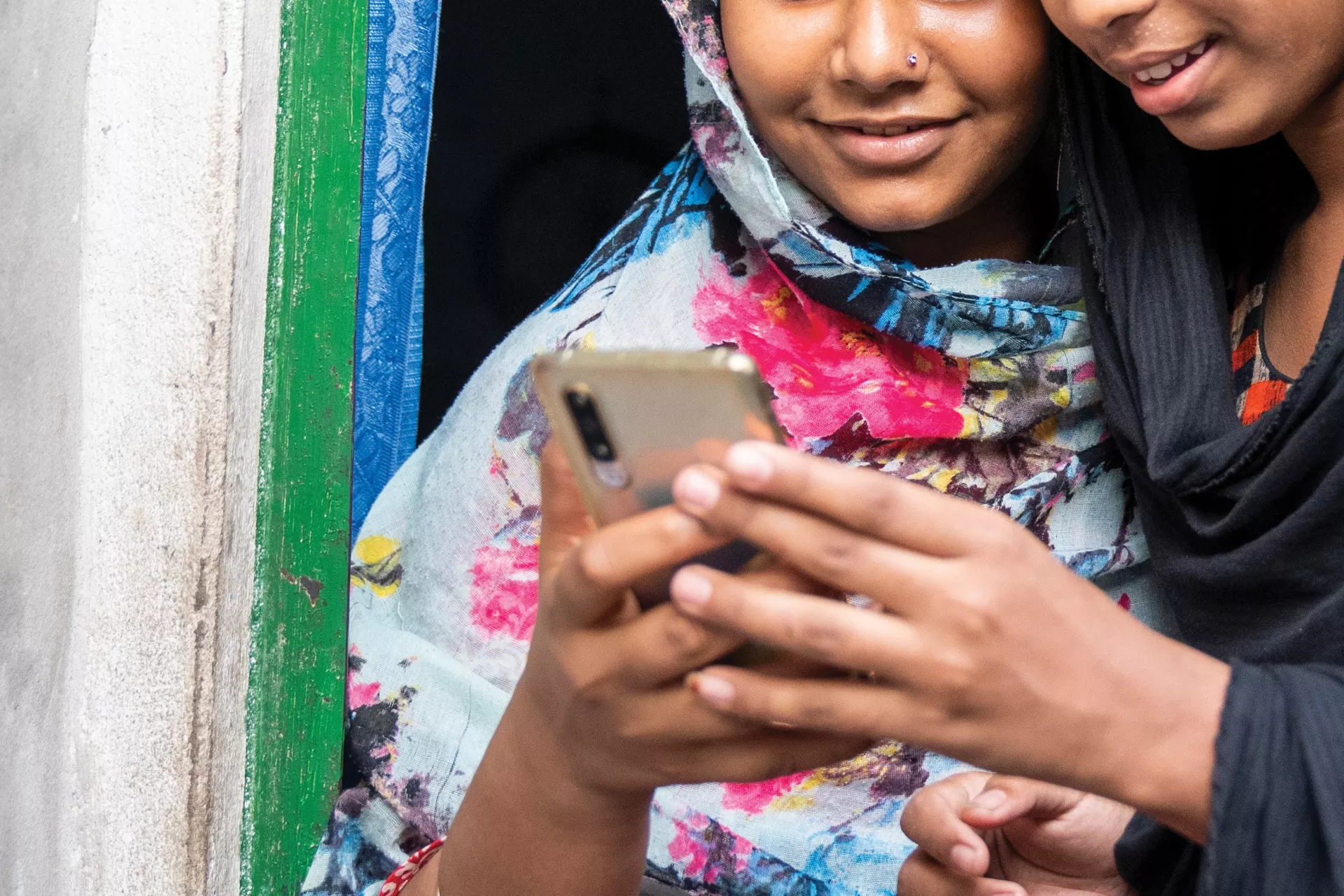 Two young girls looking at a mobil cellphone