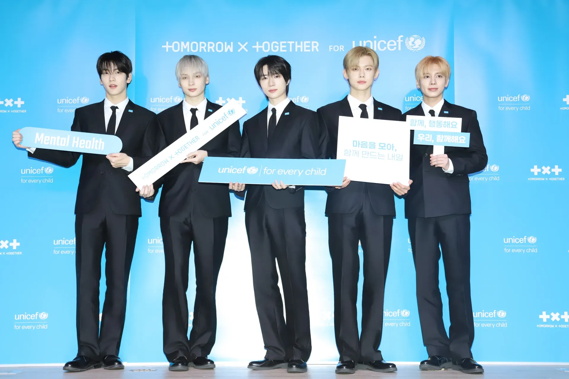 TXT members holding UNICEF and TOGETHER FOR TOMORROW campaign signs