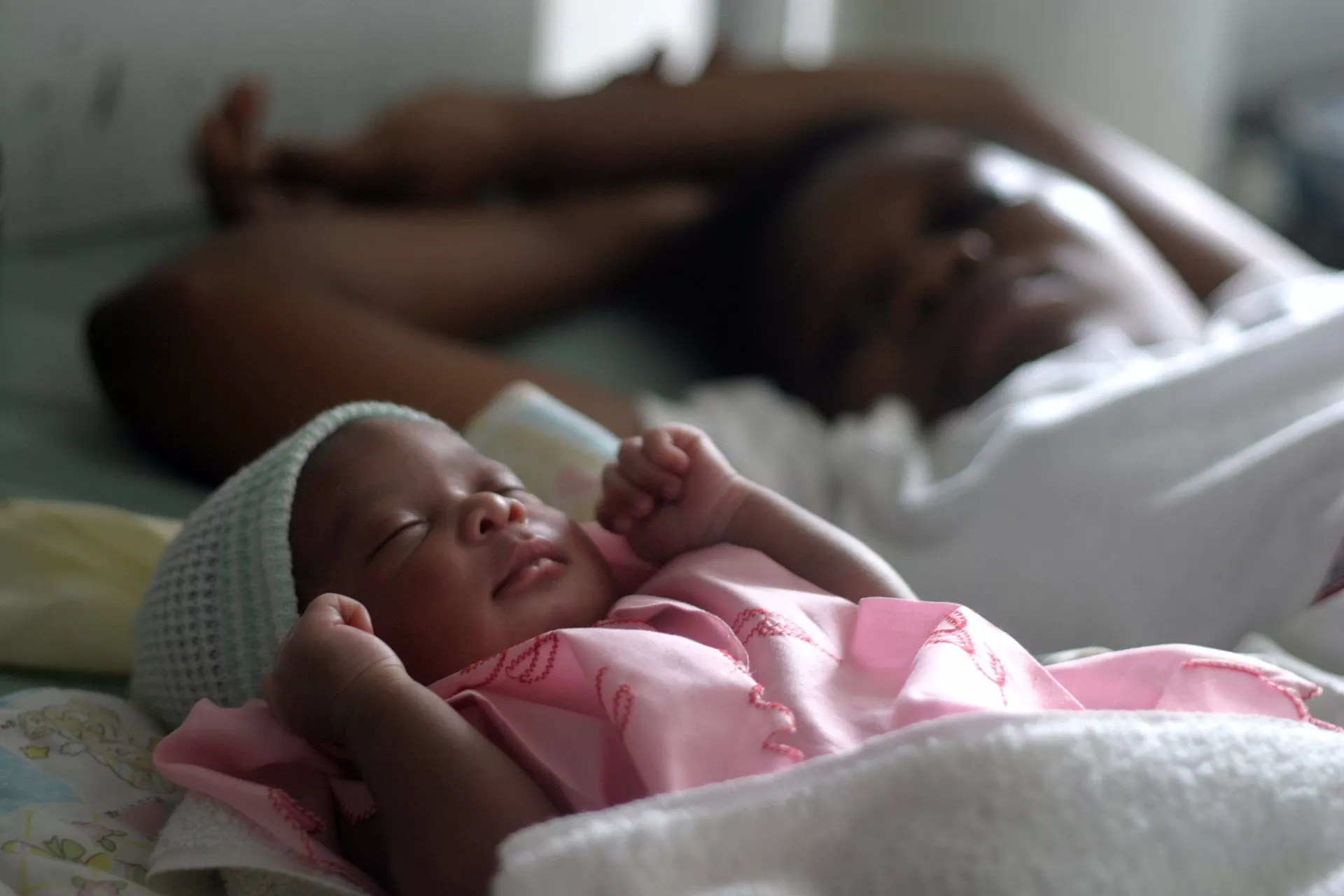 A woman rests next to her sleeping newborn in a community clinic in Haiti