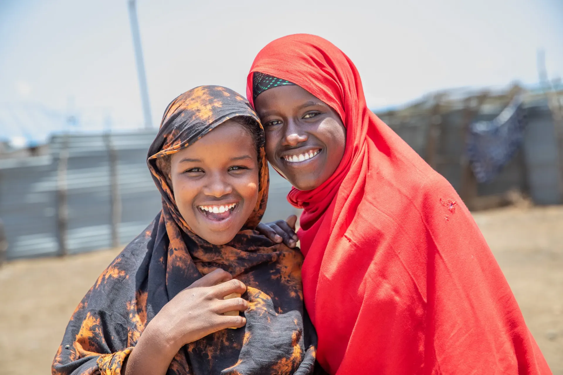 Two young, displaced girls smiling for the camera