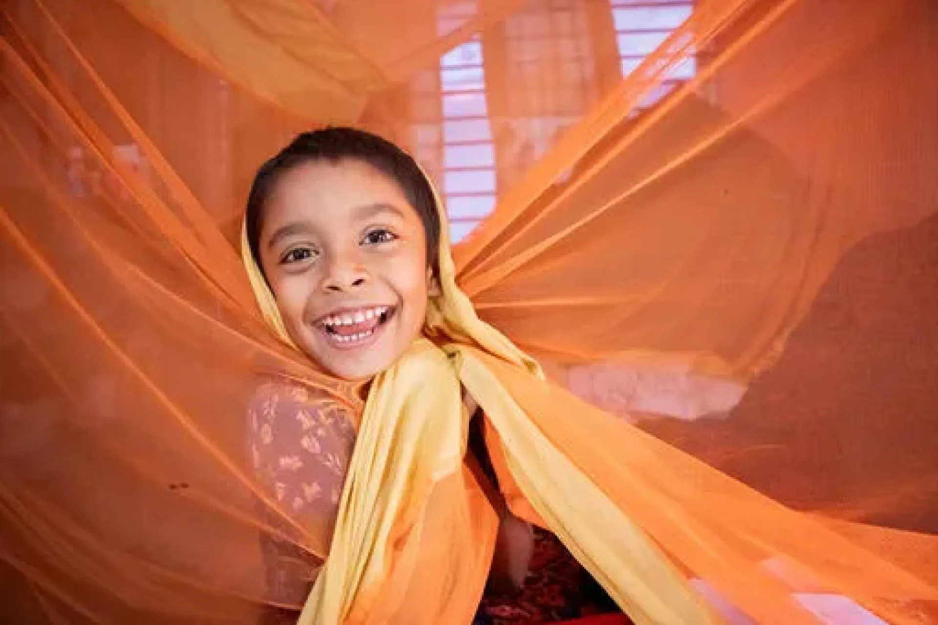 A 5-year-old child wraps himself with a mosquito net