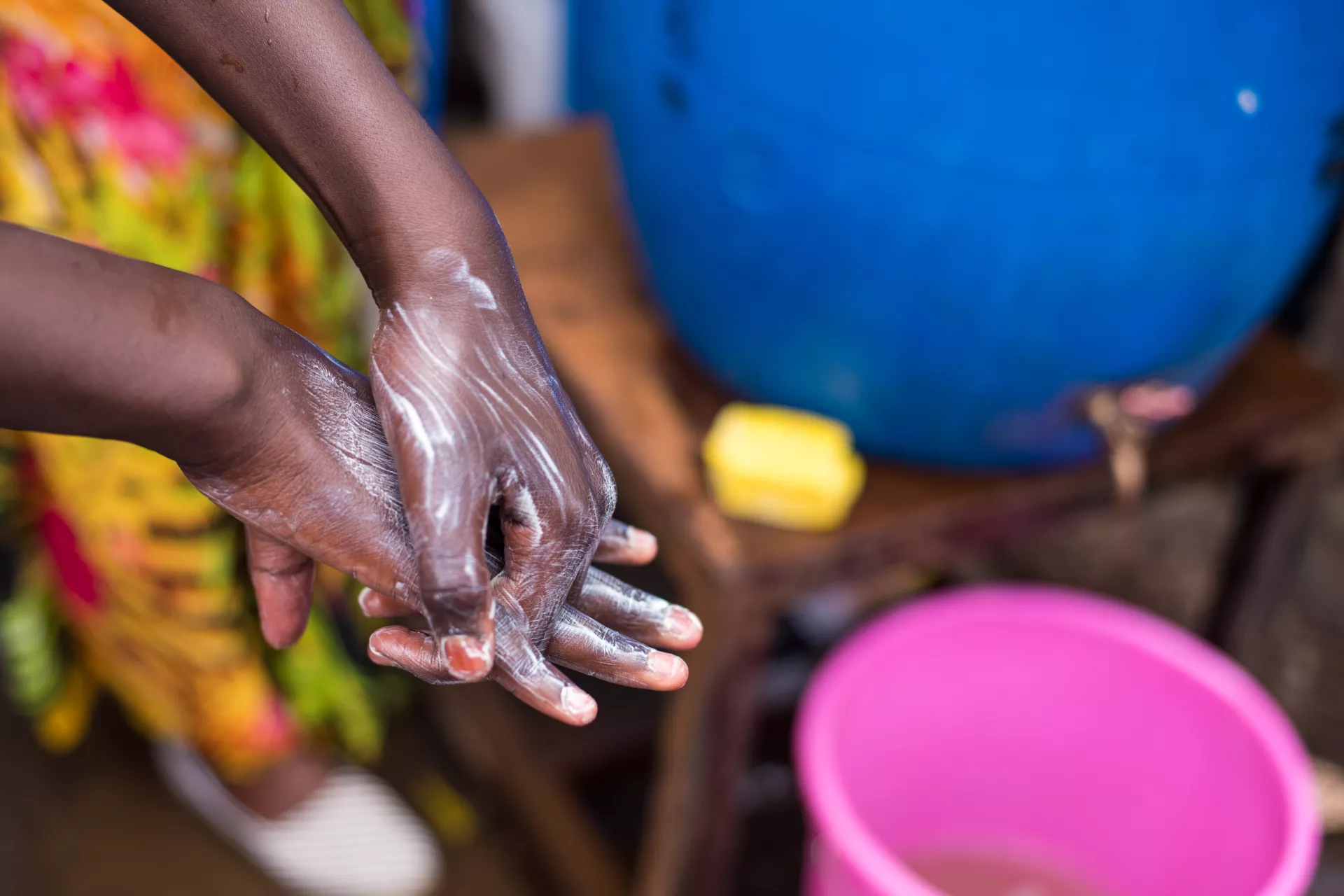 In Nairobi, Kenya, a young boy follows instructions on how to wash hands properly, at a water station in Kibera, to prevent the spread of COVID-19.