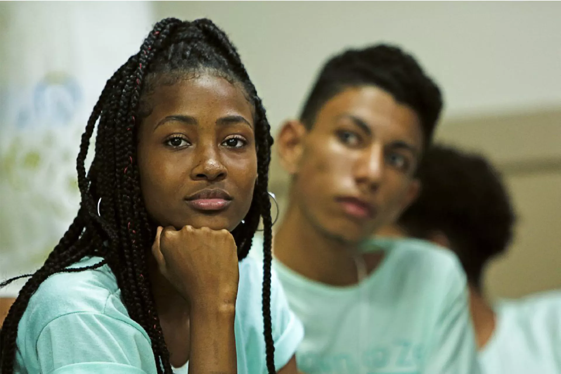 A young woman looks at the camera, her chin in her hand.