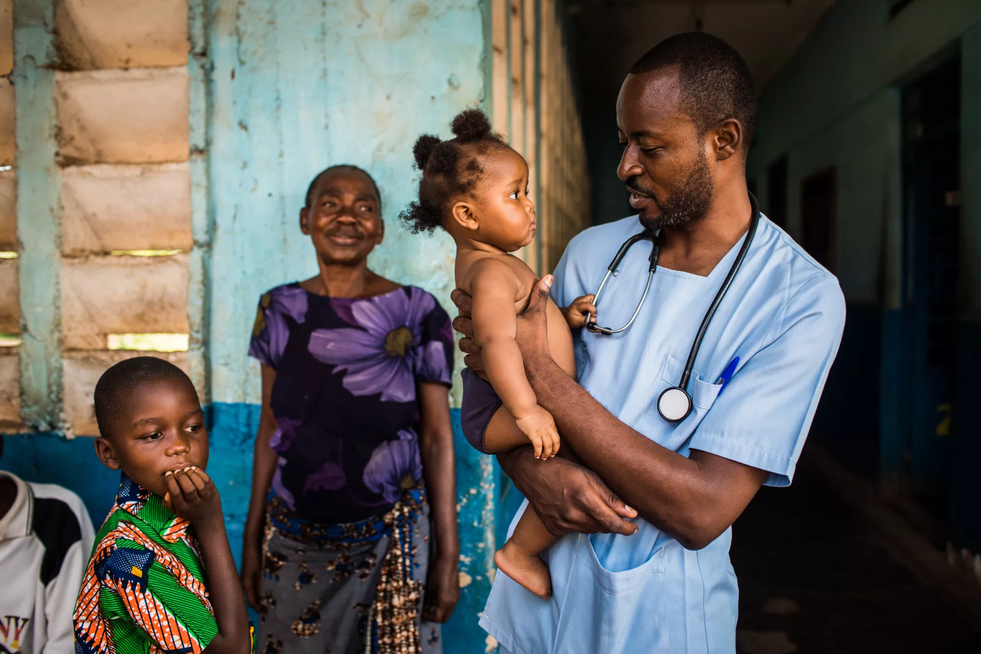 A smiling doctor holds a young girl who underwent treatment in his hospital.