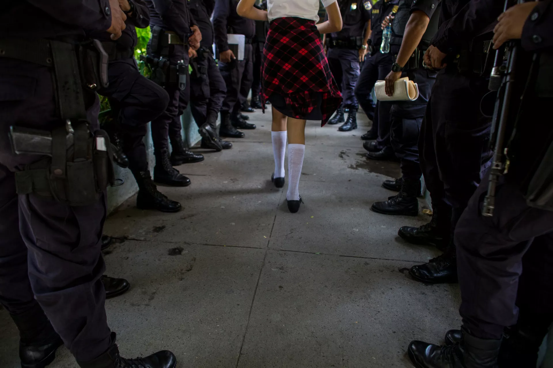 A girl walks through a queue of police officers in a classroom 