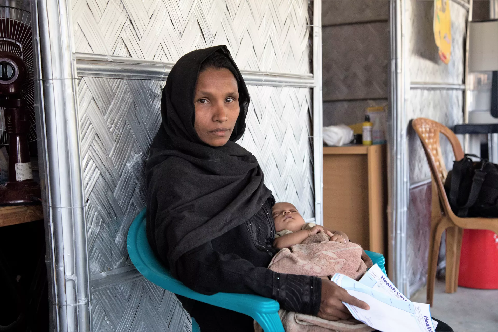 A woman sits with her son in her lap, Bangladesh