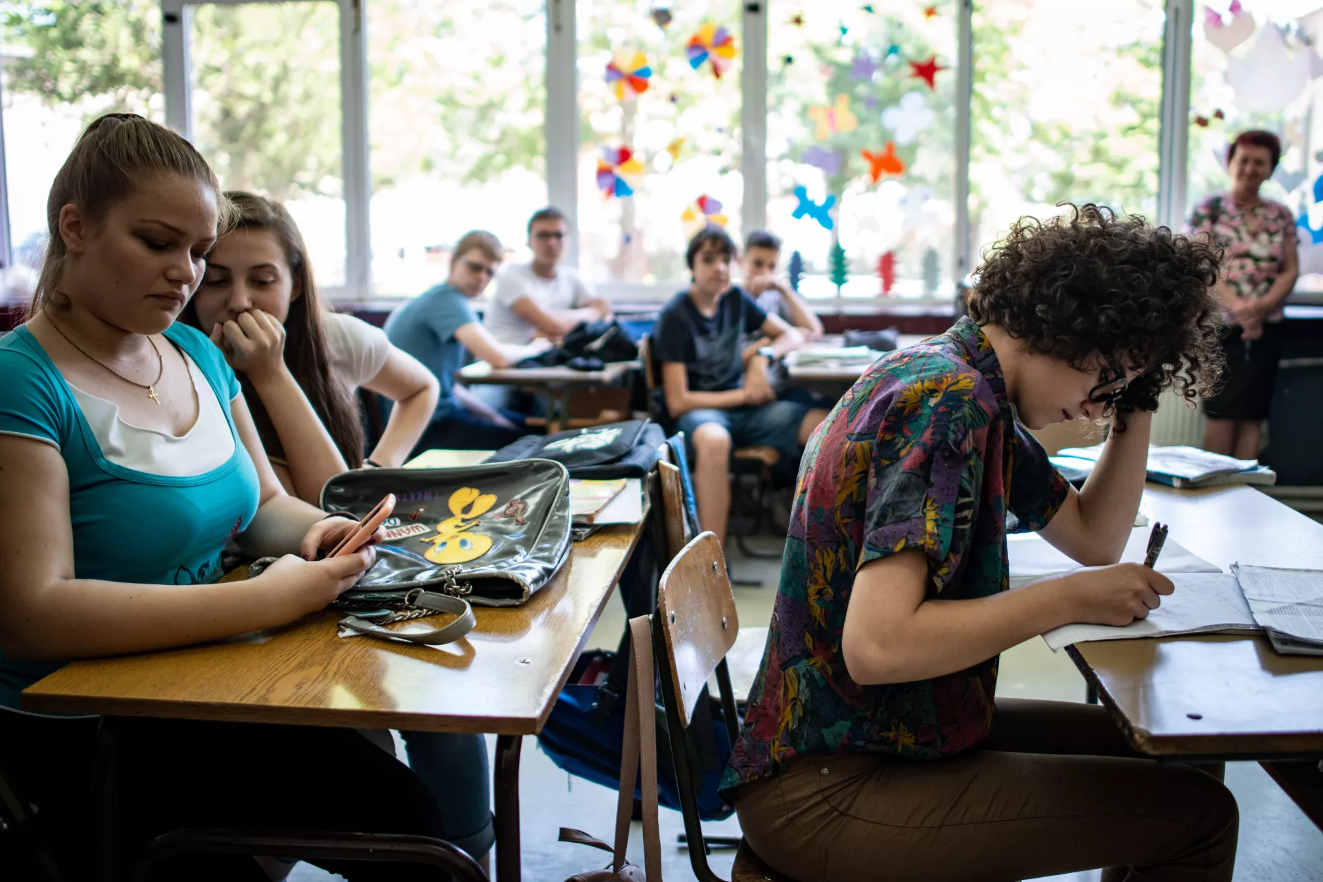 Teenagers sit at desks in a classroom