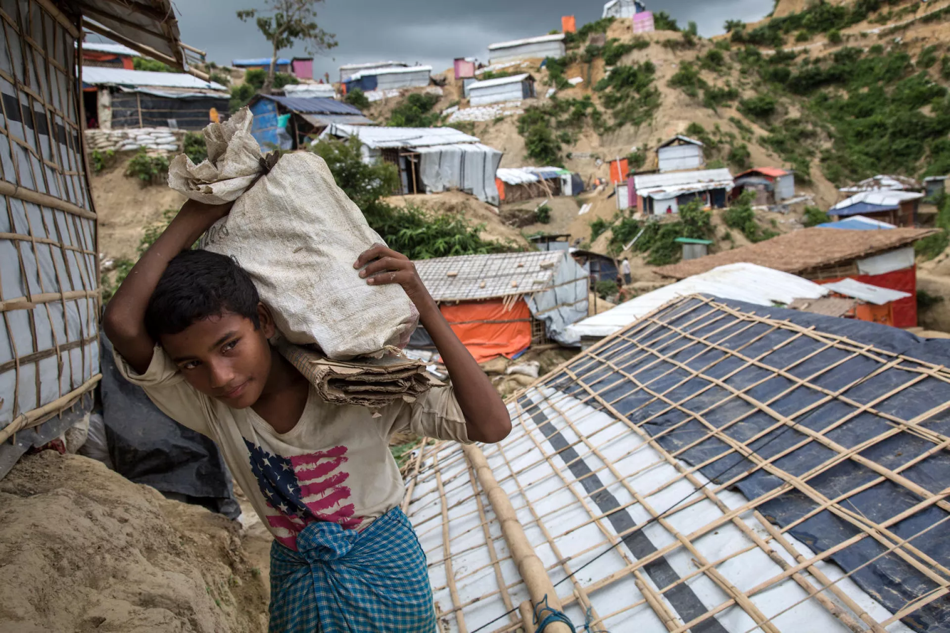 An adolescent boy carries bricks to help his family, who are Rohingya refugees, relocate to safer ground during monsoon season in Unchiprang camp, Cox's Bazar, Bangladesh.