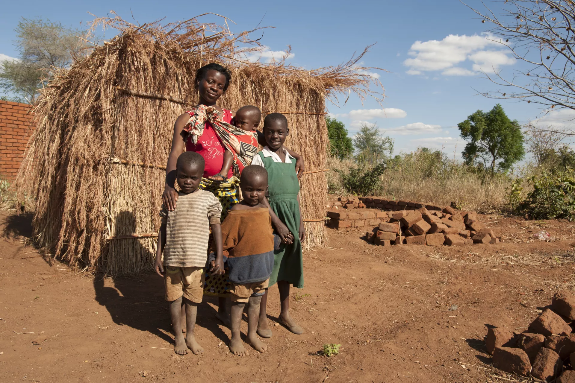 Alinafe and her family stand outside their only shelter, made from the husks of the maize plant in Balaka District in Malawi.