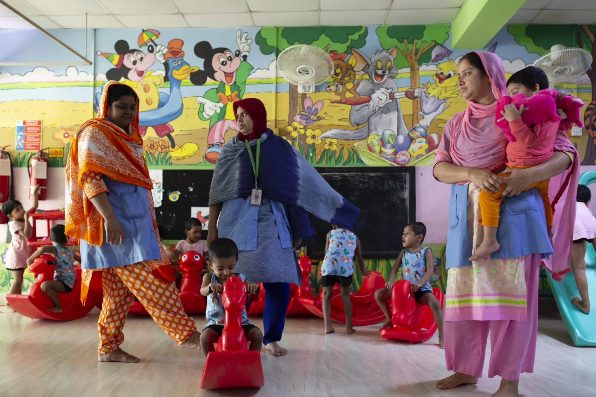 Jisha, 3, is held by a caregiver at the Early Childhood Development (ECD) day care centre located on the Fakir Fashion Ltd. factory where both her parents work in Narayangonj, outside Dhaka, Bangladesh
