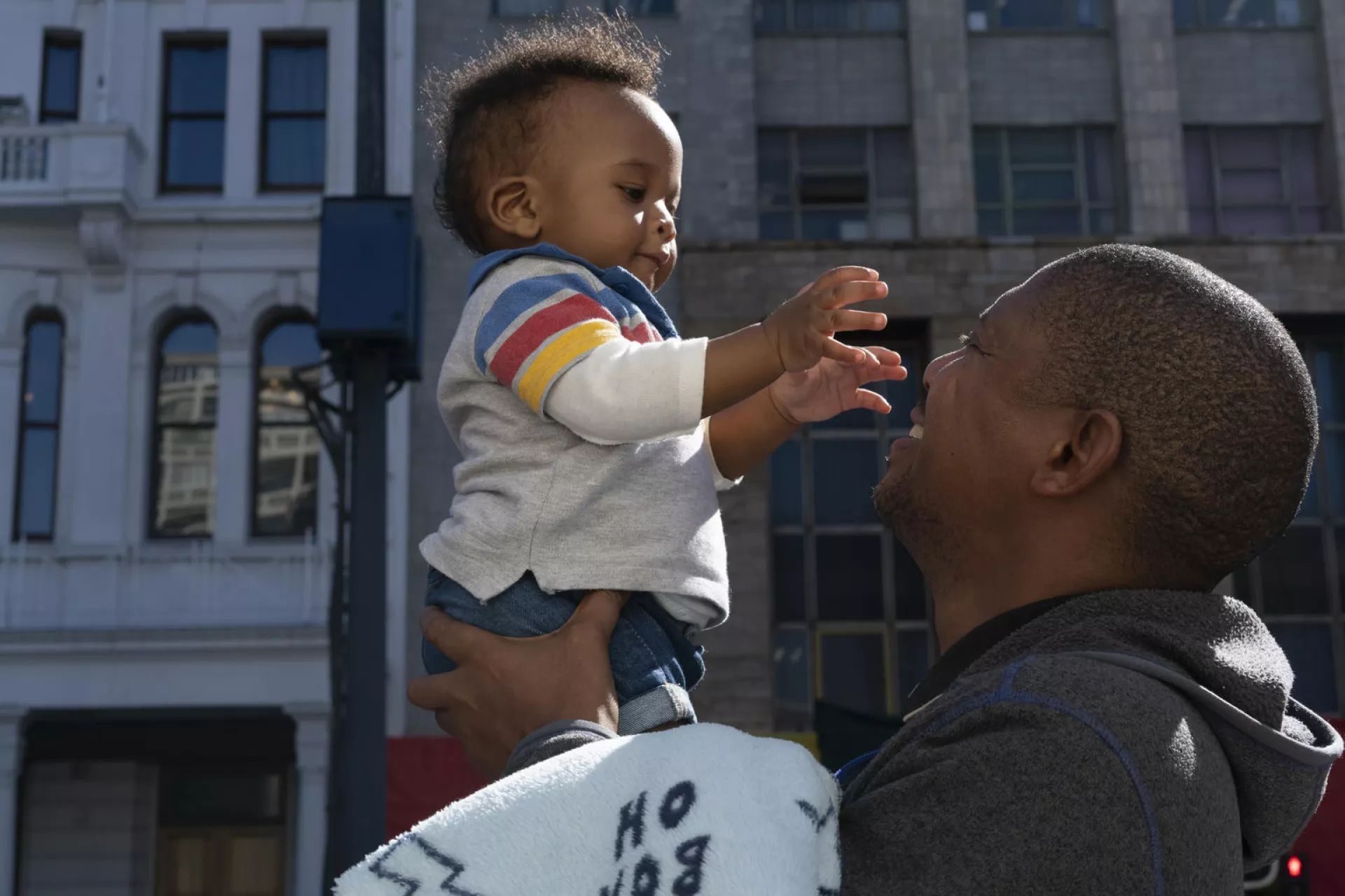 Sunlight filters though the trees of a quiet park in central Cape Town, South Africa as Bongani Ngqame, 44, holds his son Khuma, 8 months. 