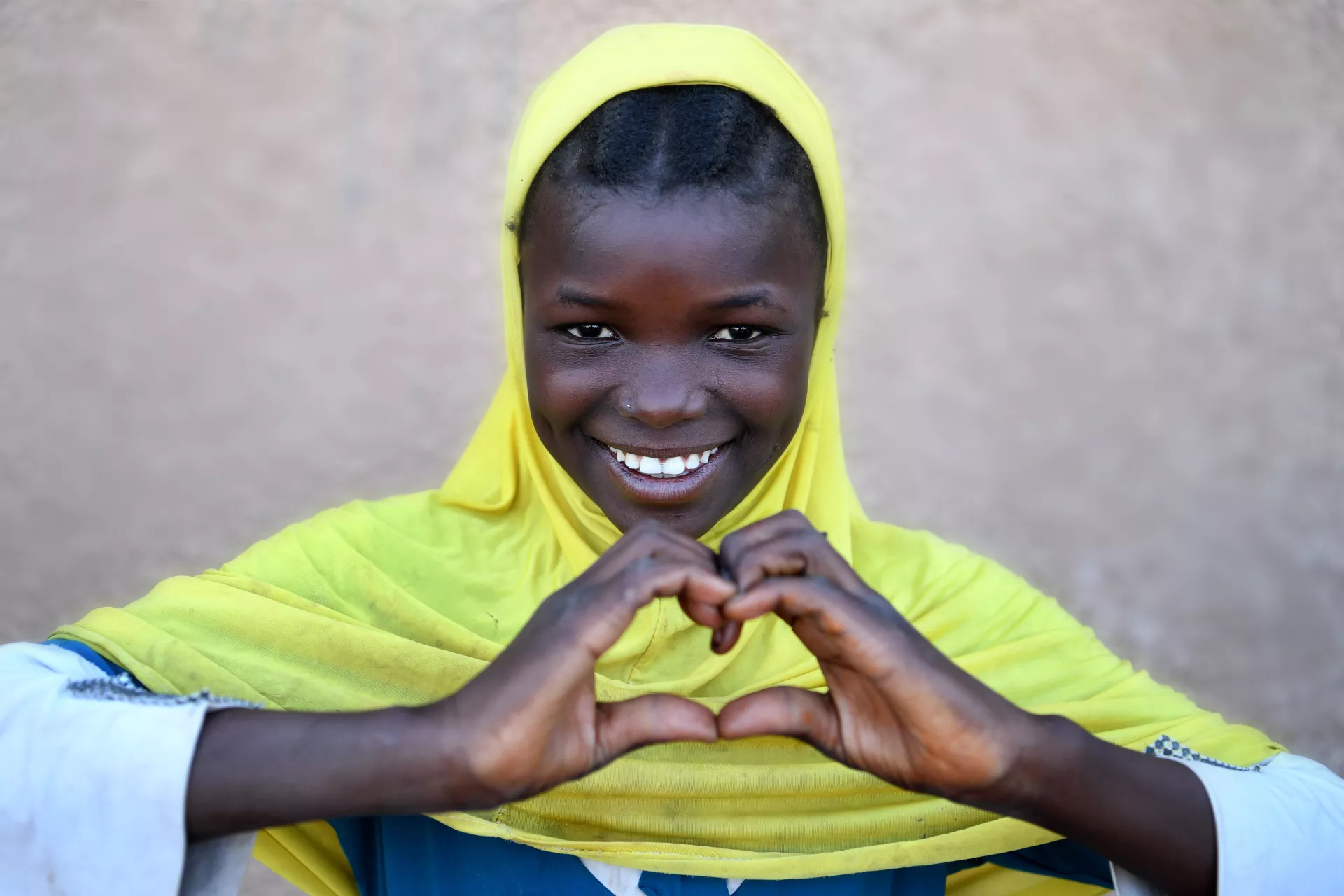 Niger. A girl creates a heart sign with her hands at a transit centre in Agadez, northern Niger.