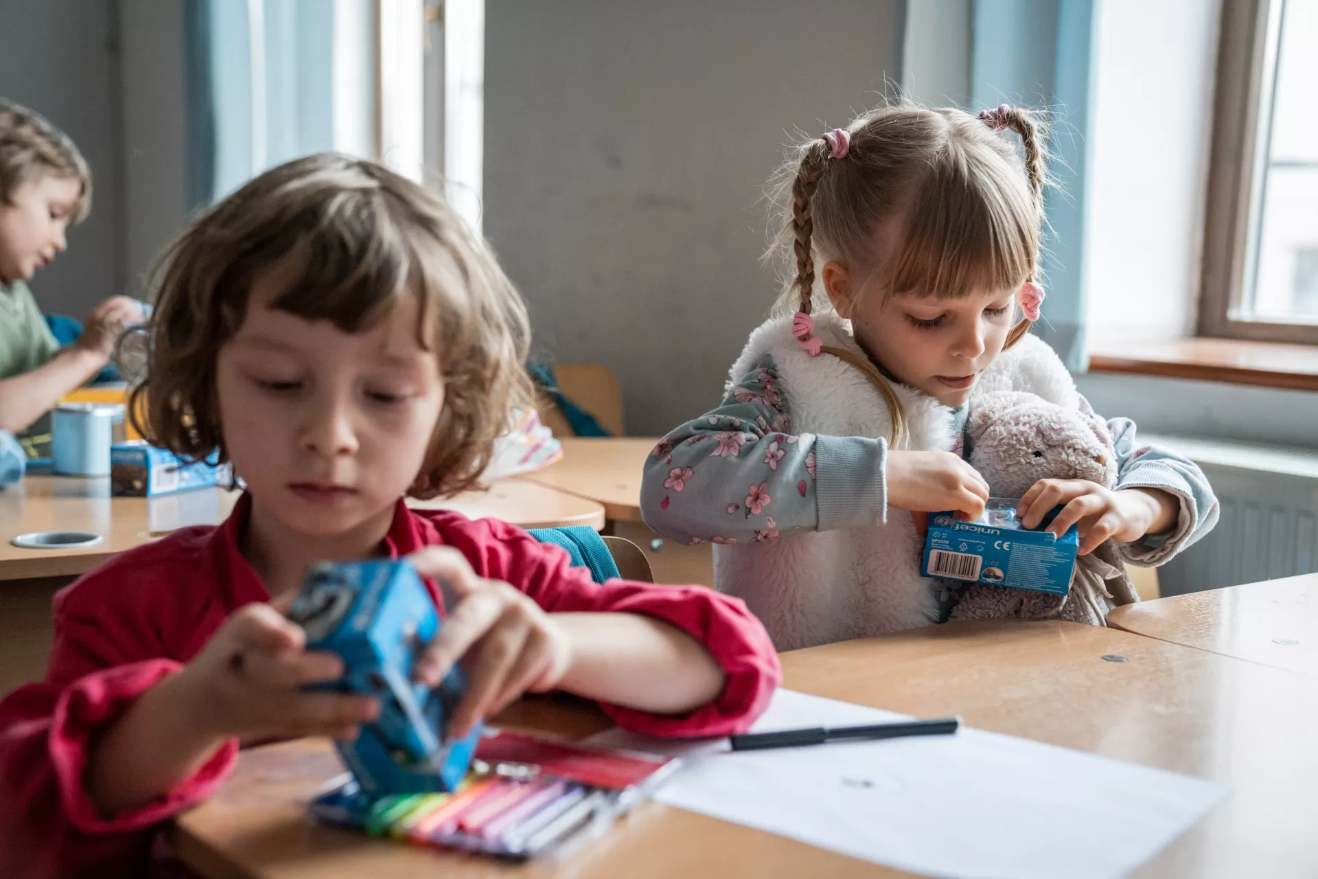 Romania. Two children sit at their desks playing in a classroom.