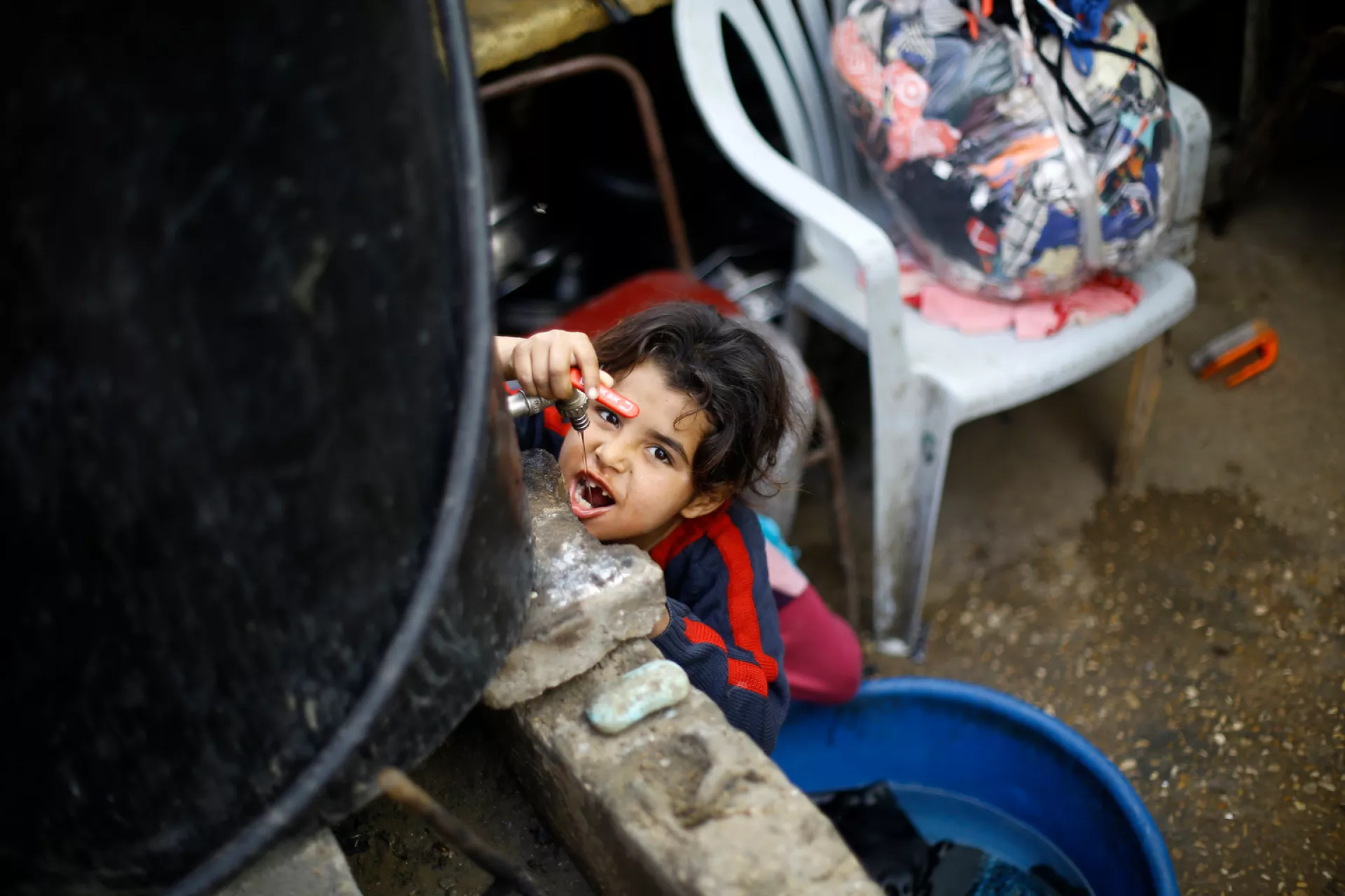Eight-year-old Sawsan drinks water from a container outside the tin-roofed shack