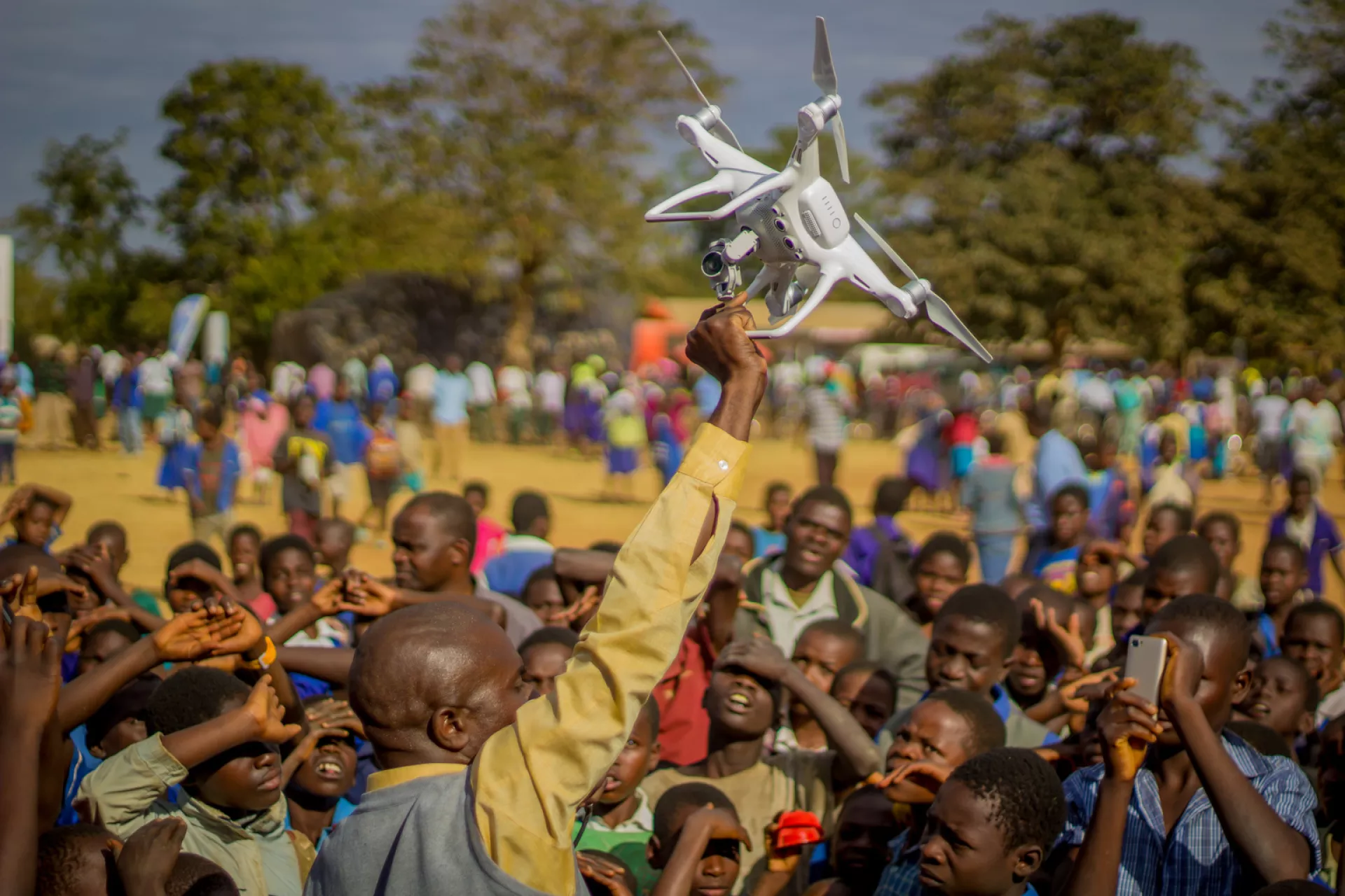 A man in Malawi holds up a drone at a community demonstration
