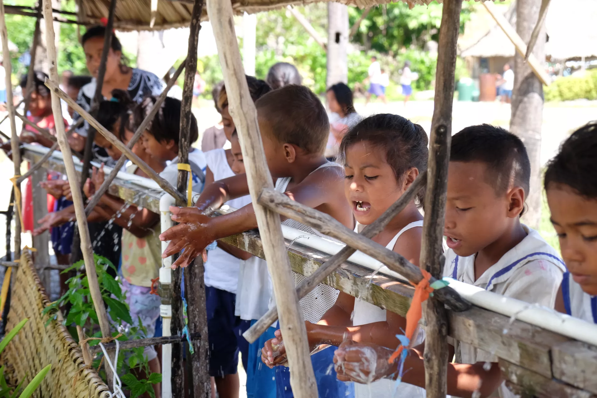 Young children in Kiribati wash their hands outside in 2019.