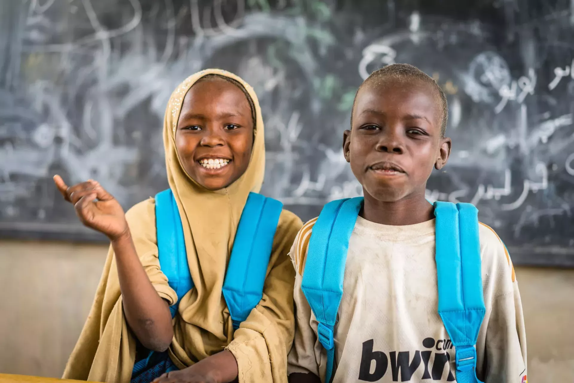 Students stand in front of a blackboard. They are smiling.