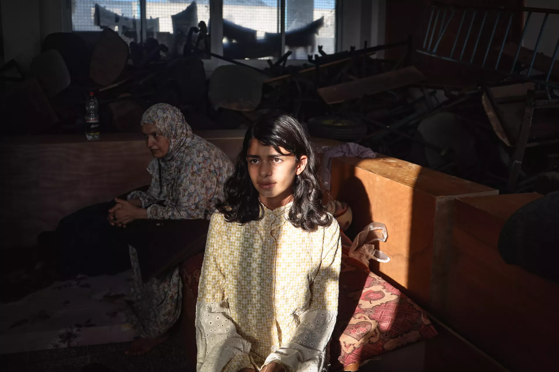 Ghazal, 14, from Khuza&rsquo;ah Village, eastern Khan Younis City, in southern Gaza Strip in November 2023, sits surrounded by detritus inside. A small beam of sunlight shines across her face.