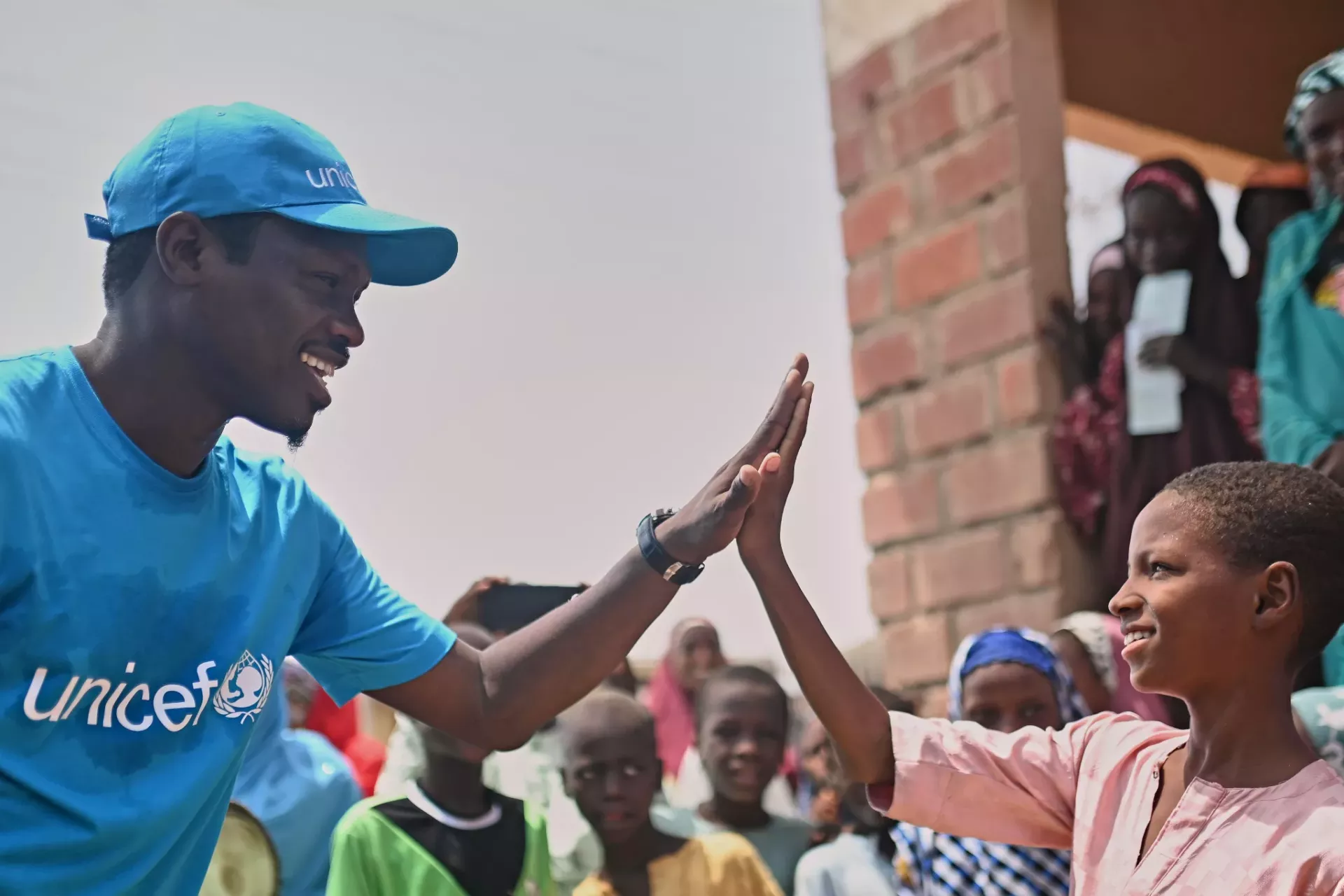 Ali Nuhu, A Nigerian Actor and Unicef Champion gives a high five to a boy during a visit to Tsamiyya Babban PHC, Kano State